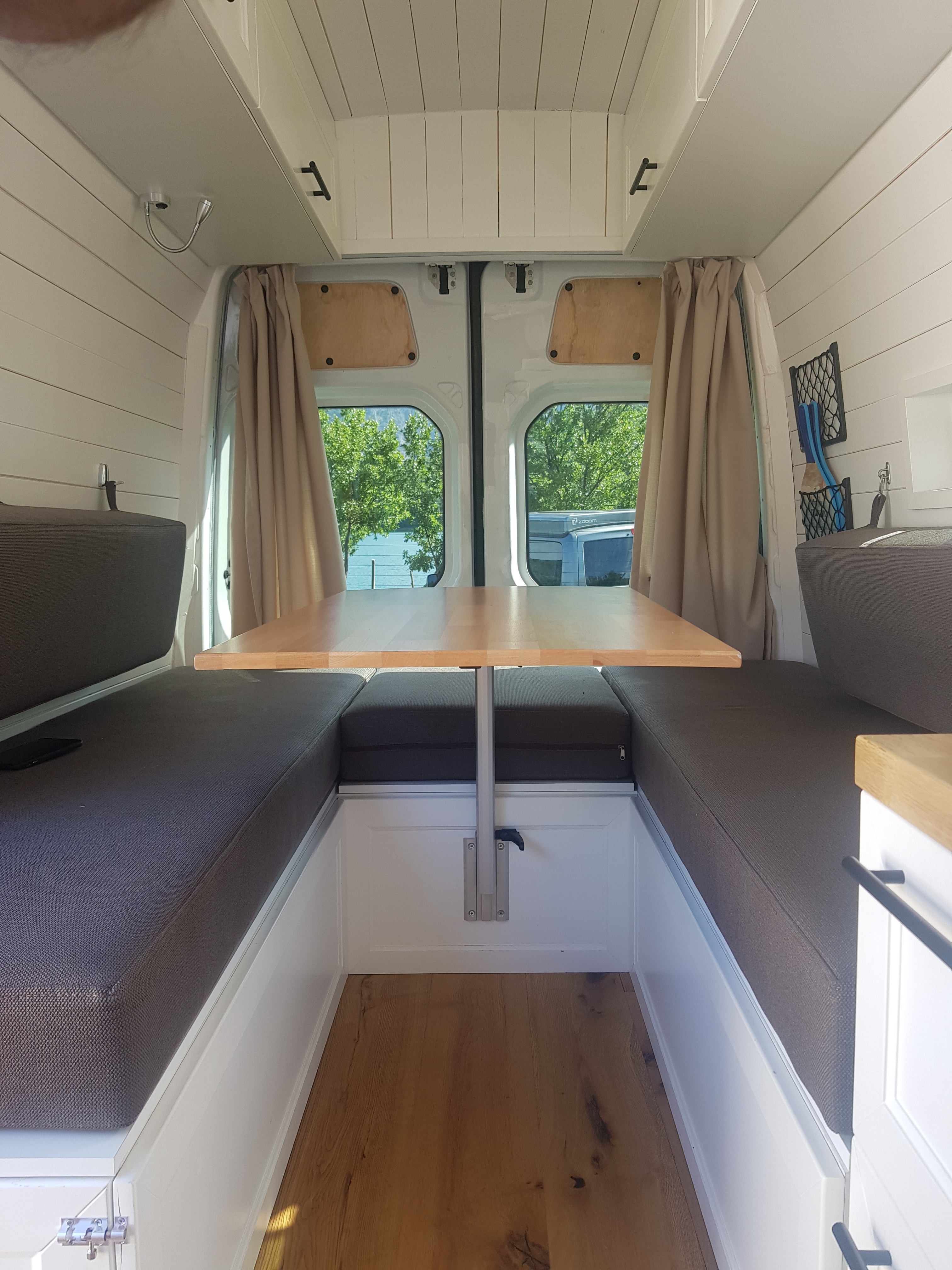 Interior view of the DIY Mercedes Sprinter camper van, showcasing a cozy living space with seating and a table.